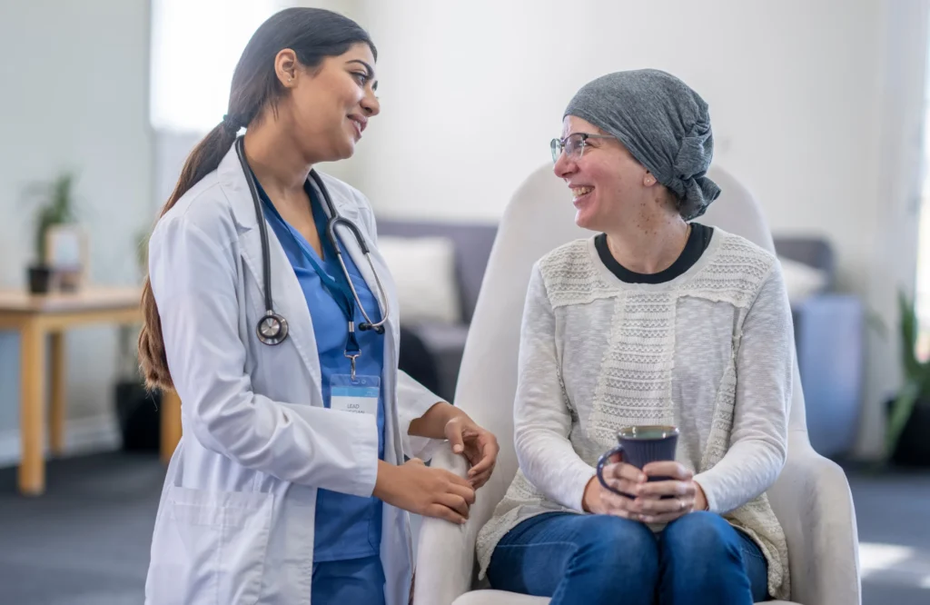 A compassionate doctor talking with a smiling patient during treatment, representing quality Cancer Care in Banjara Hills.
